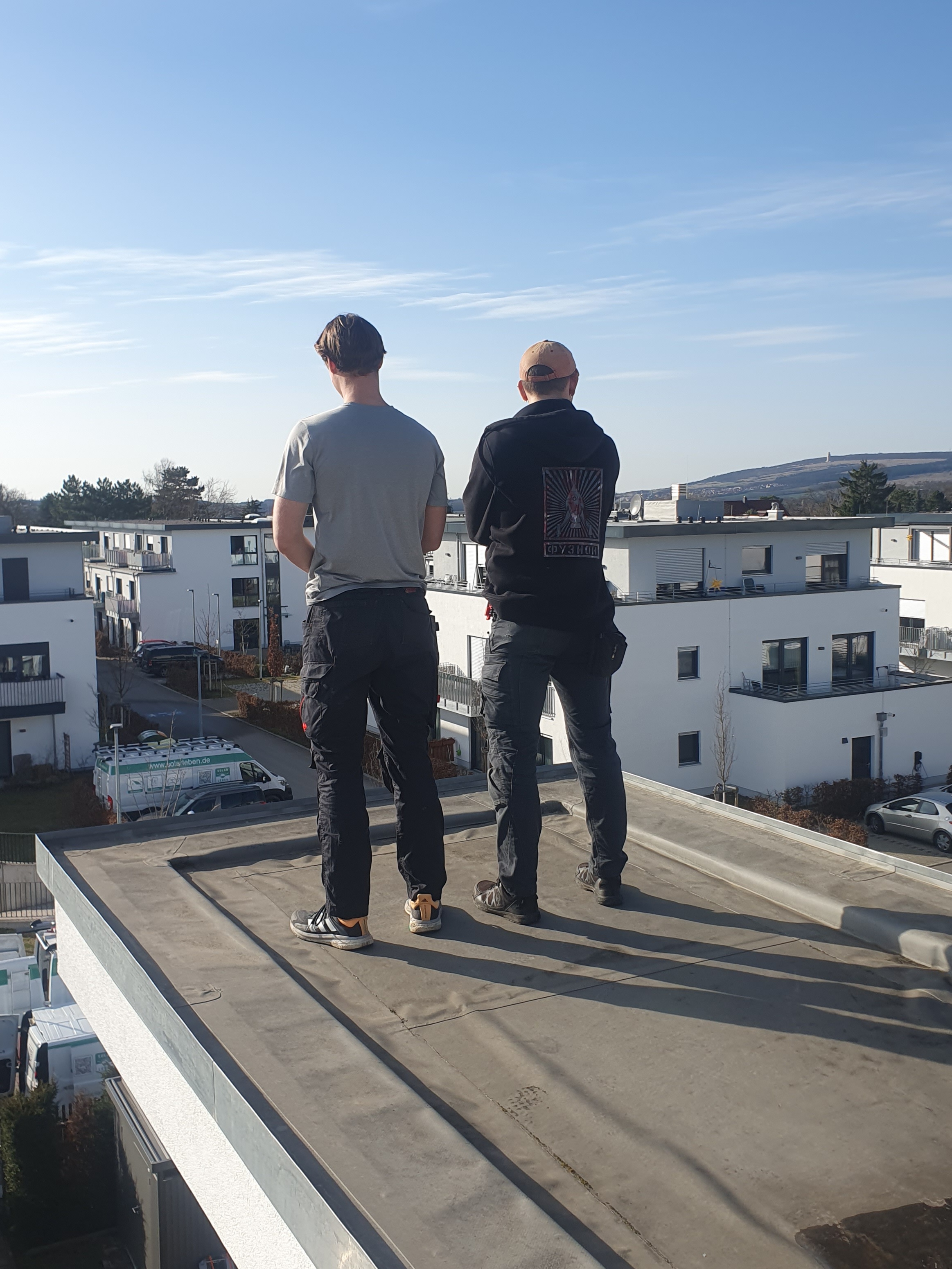 Zwei Monteure auf Flachdach bei der Planung einer Photovoltaikanlage